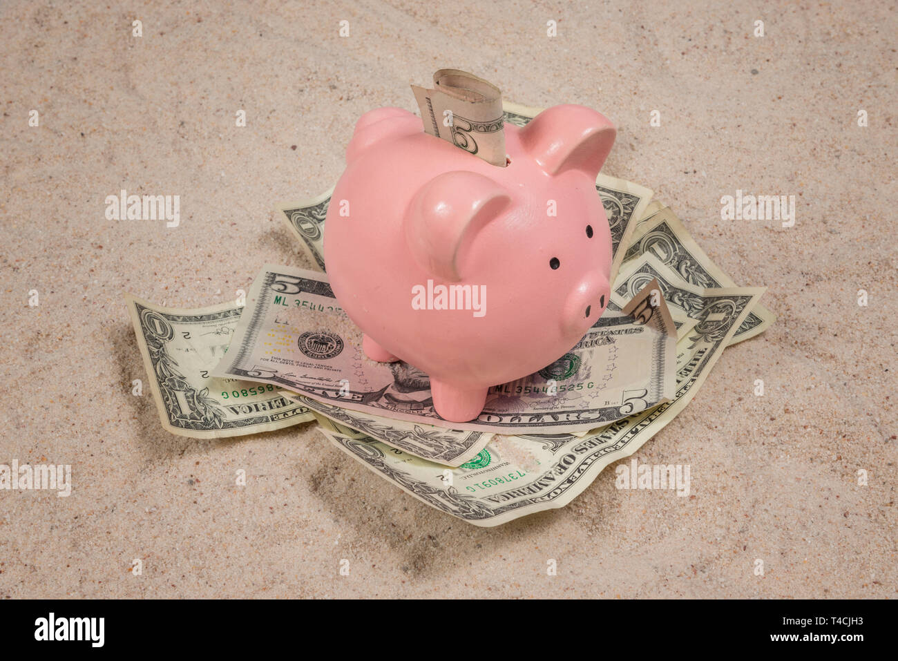 Inquadratura orizzontale di un rosa salvadanaio su un mucchio di soldi con  il denaro nel suo slot tutti su una spiaggia di sabbia sullo sfondo Foto  stock - Alamy