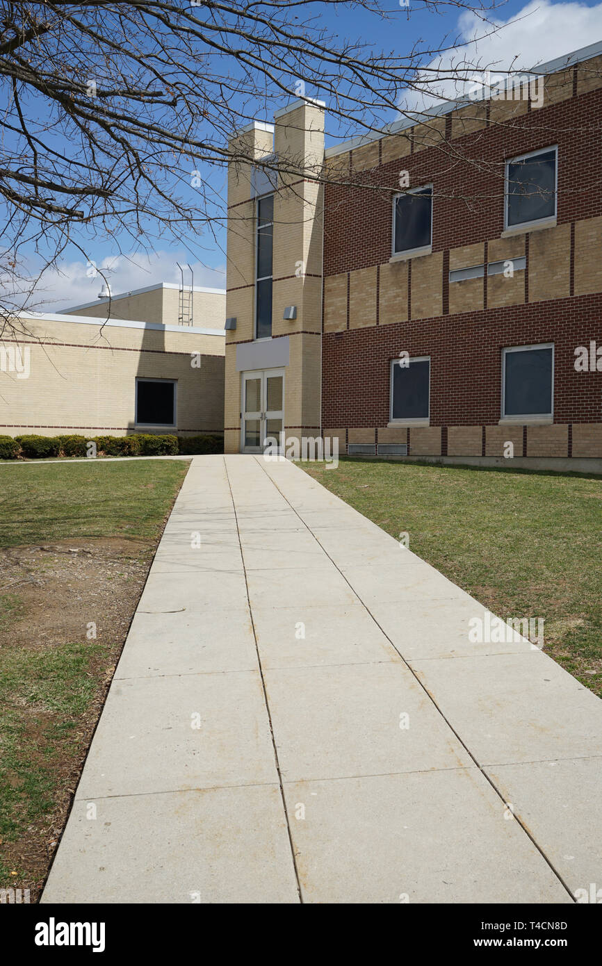 Un calcestruzzo lungo il marciapiede conduce all'ingresso per una scuola builidng. La facciata della struttura è fatta di mattoni. Questa è l'area di Bangor High School Foto Stock