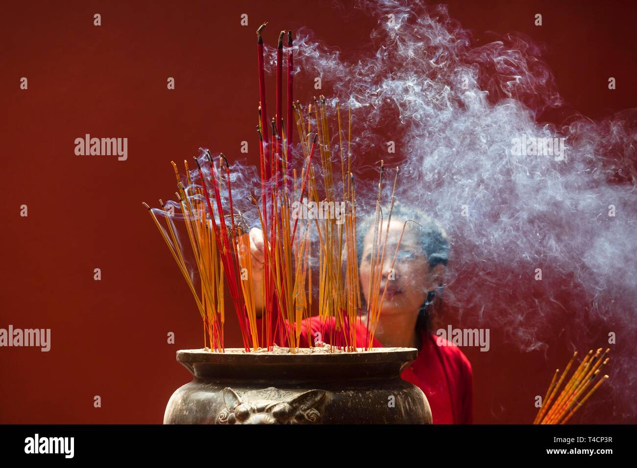 Giovane donna con la masterizzazione di bastoncini di incenso sul nuovo anno cinese, complesso tempio Wat Phnom Penh Daun, Phnom Penh Cambogia Foto Stock