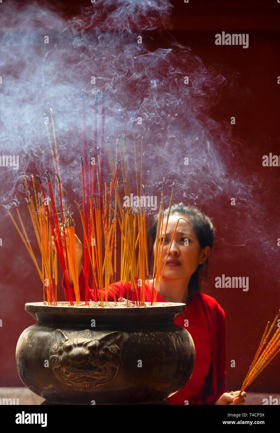 Giovane donna con la masterizzazione di bastoncini di incenso sul nuovo anno cinese, complesso tempio Wat Phnom Penh Daun, Phnom Penh Cambogia Foto Stock