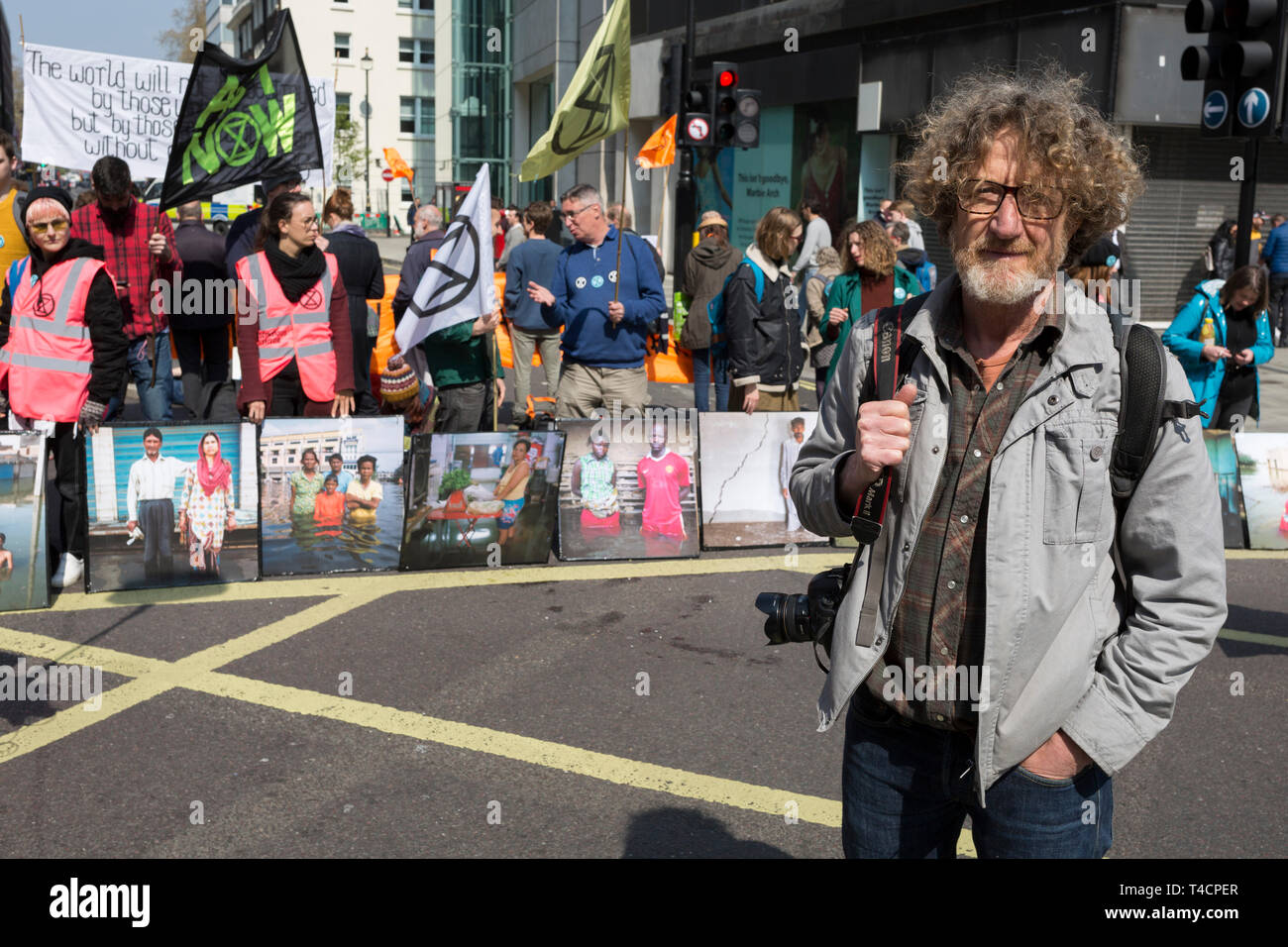 Fotografo Gideon Mendel e alcune delle sue vittime alluvione ritratti 'Drowning mondo' durante il cambiamento climatico protestare con estinzione della ribellione bloccando Oxford Street e contemporaneamente fermare il traffico attraverso il centro di Londra tra cui Marble Arch, Piccadilly Circus, Waterloo Bridge e le strade attorno a Piazza del Parlamento, il 15 aprile 2019, a Londra, in Inghilterra. Foto Stock