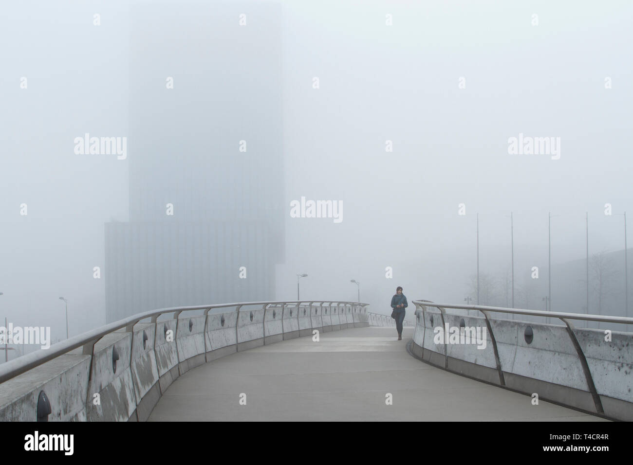 Lonely Donna che cammina su una mattinata nebbiosa nella città Foto Stock Lonely Donna che cammina su una mattinata nebbiosa nella città Foto Stock