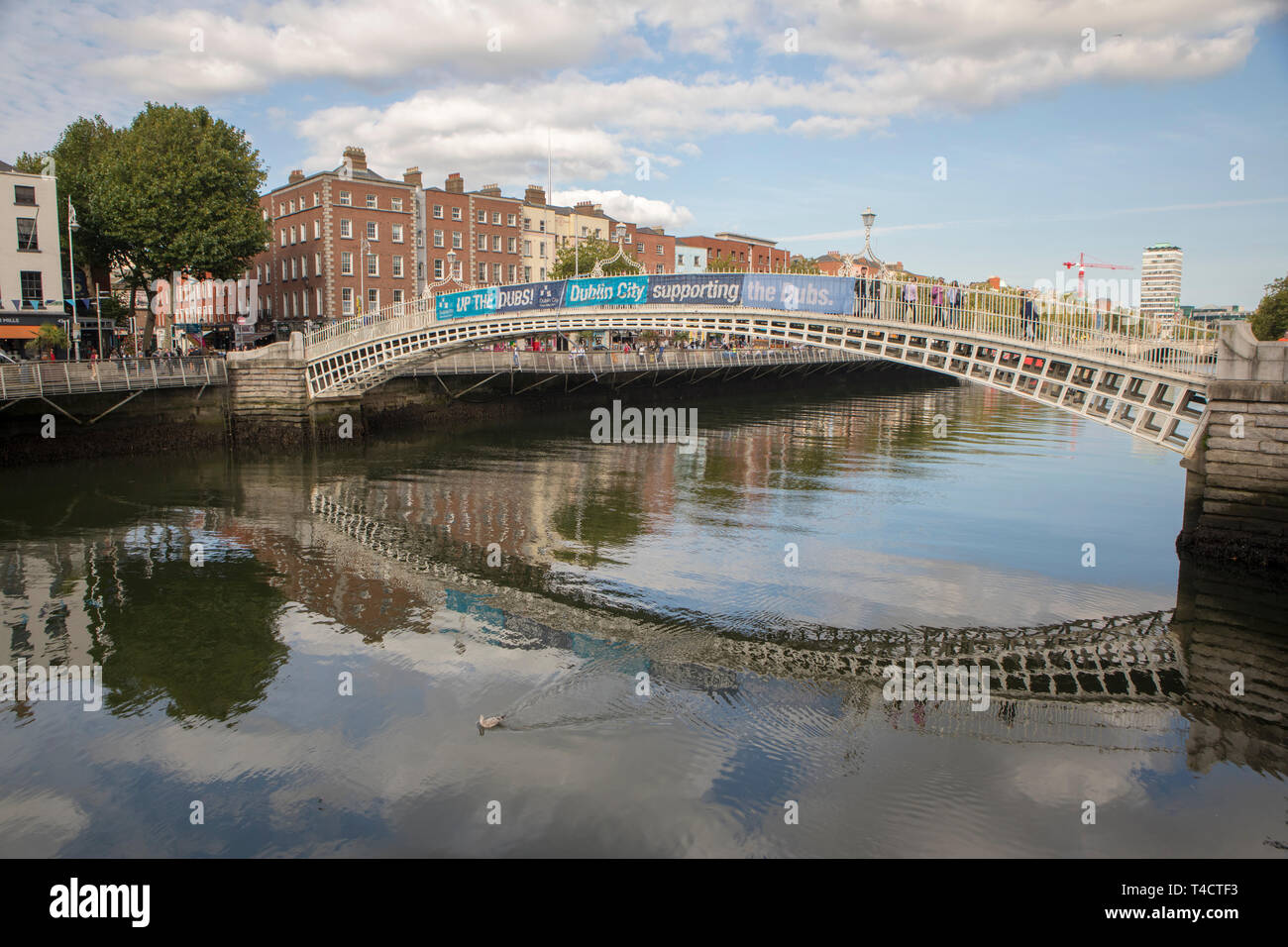 Ha'penny Bridge a Dublino si riflette nel fiume Liffey. Foto Stock