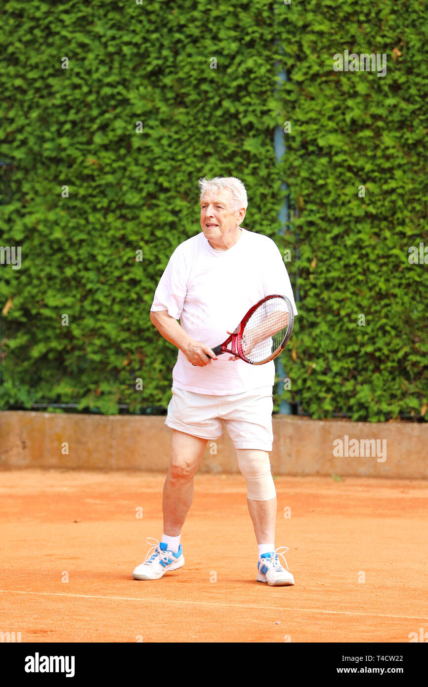 Il vecchio uomo attivo giocare a tennis in estate Foto Stock