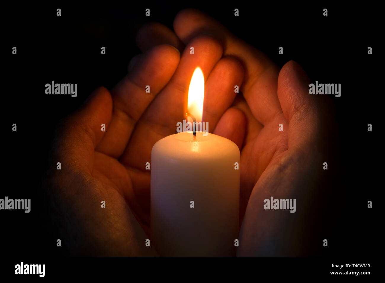Le mani umane tenendo una candela che brucia nel buio Foto stock - Alamy