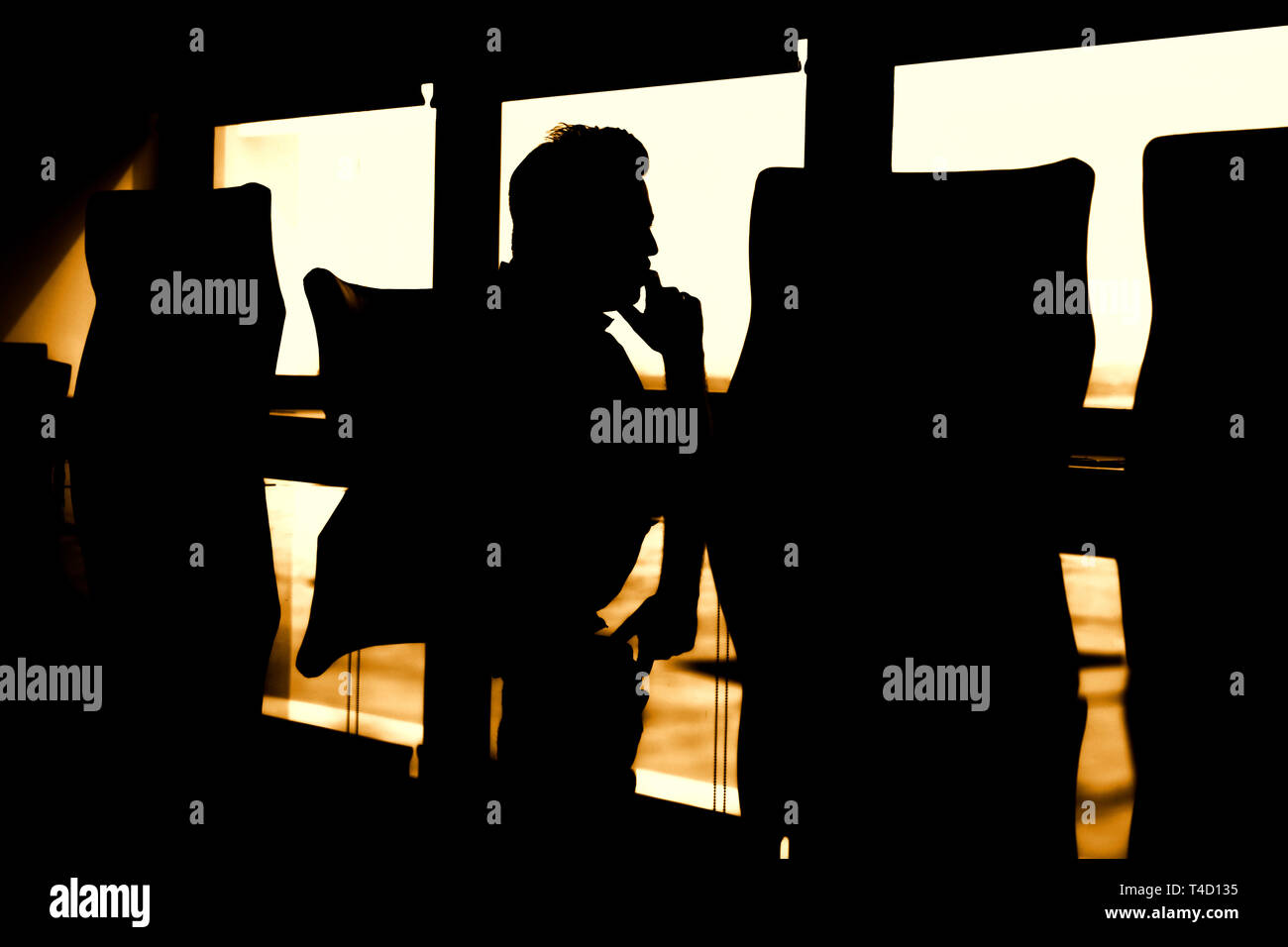 Silhouette nera dell'uomo a tavola, pensando malinconici pensieri profondi. Foto Stock