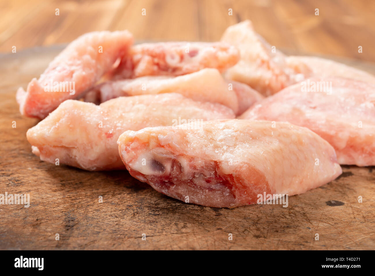 Vista laterale congelati materie ali di pollo sulla scheda di trinciatura Foto Stock