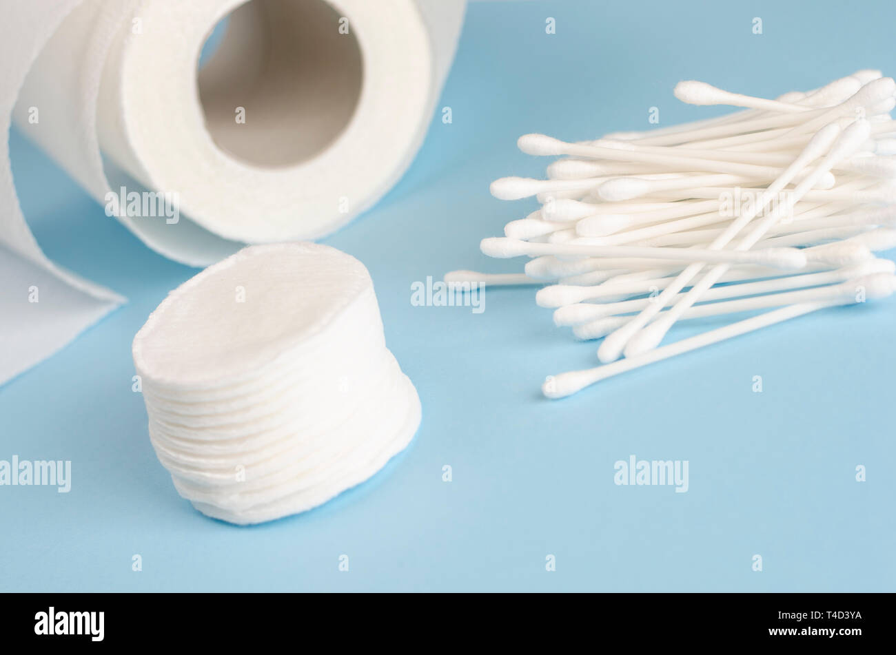 Orecchio bastoni, tamponi di cotone e carta igienica rotolo sul pastello blu sullo sfondo. Cura del corpo concetto. Spazio di copia Foto Stock