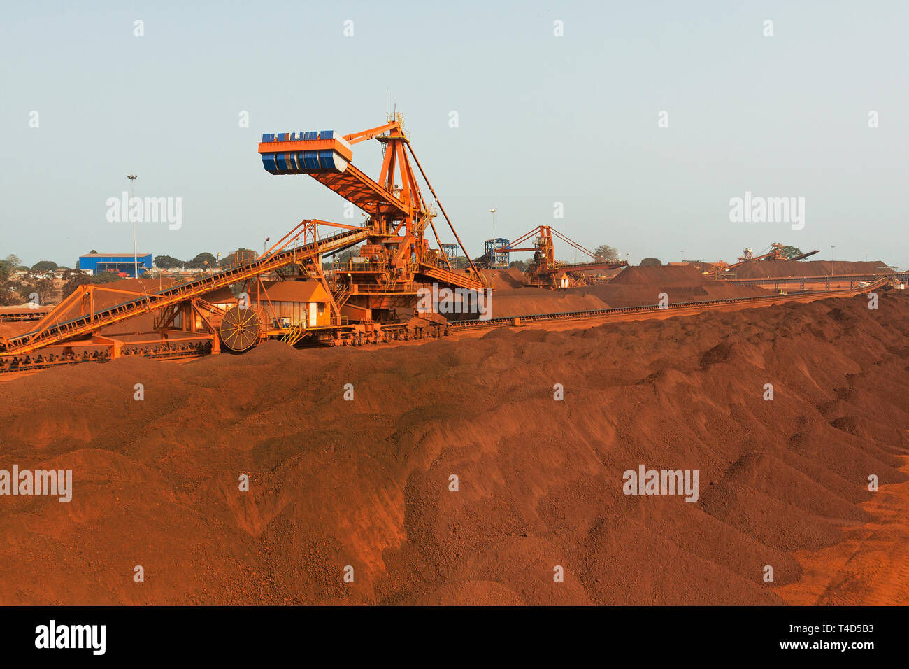 Operazioni portuali per la gestione e il trasporto di minerale di ferro. Su stock pile al raccoglitore reclaimer & di nuova costruzione impilatrice con farfalla impilatore in distanza Foto Stock