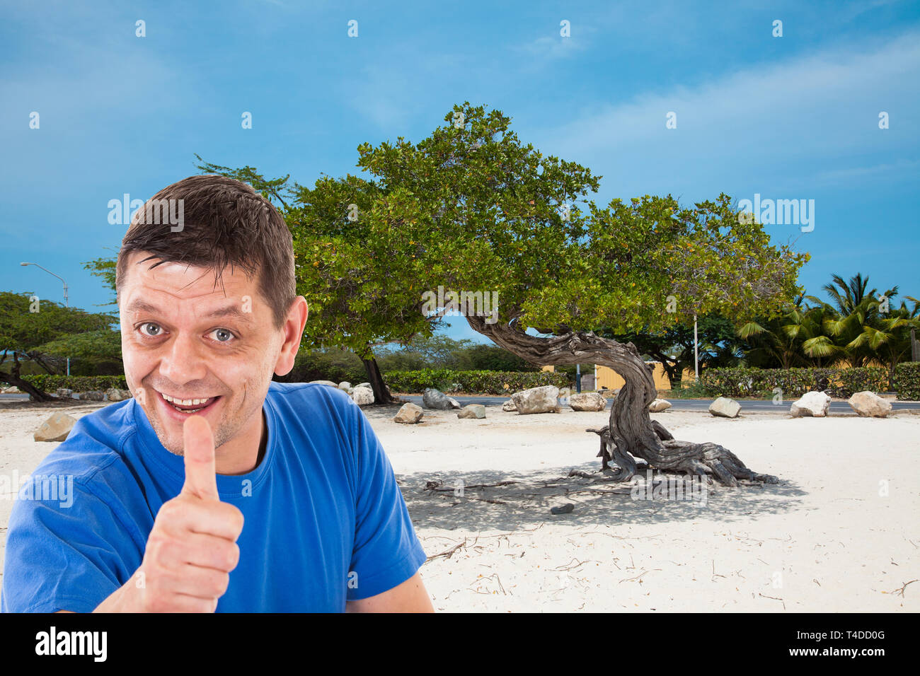 Uomo di fronte spiaggia di Aruba con il pollice in alto Foto Stock