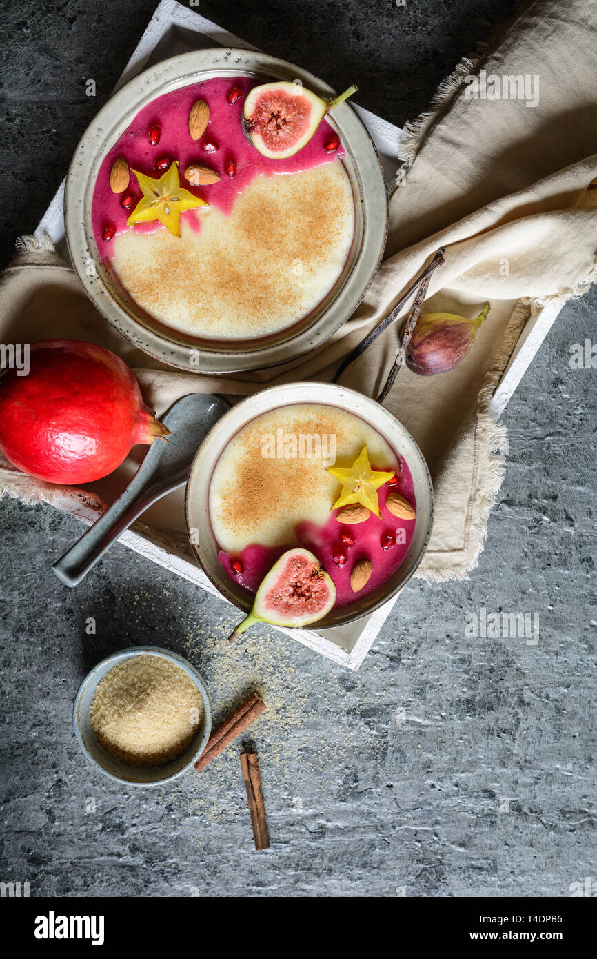 Budino di semolino con fatti in casa di sciroppo di melograno, decorata con star fruit, di fichi e mandorle Foto Stock