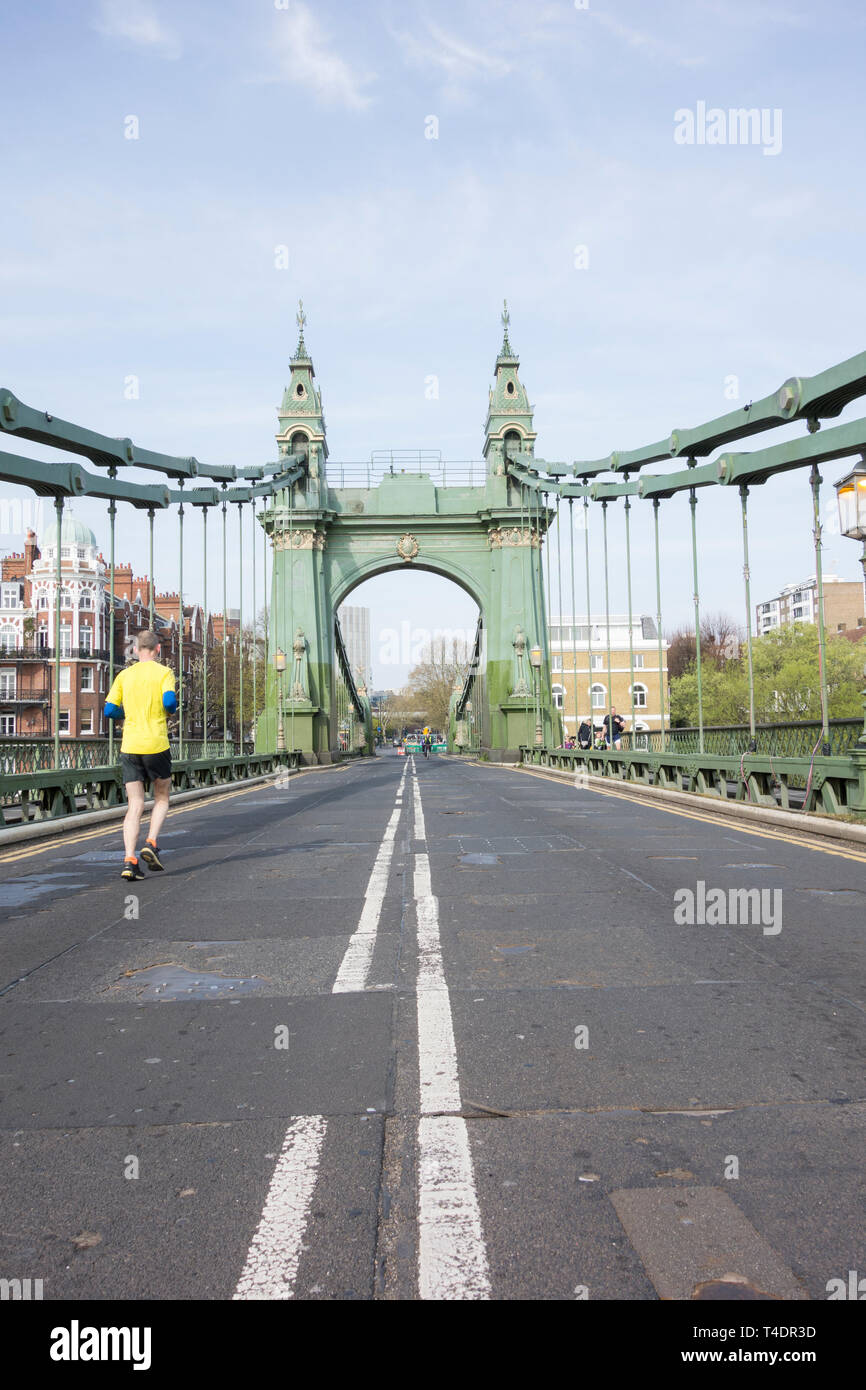 Un pareggiatore corre sopra Hammersmith Bridge che ora è stata chiusa a tempo indeterminato per autovetture e autobus ma ancora aperta per i pedoni e i ciclisti Foto Stock
