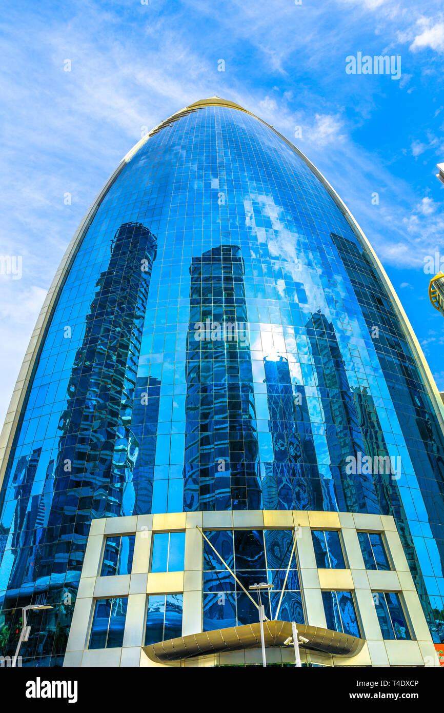 Doha, Qatar - 17 Febbraio 2019: Woqod Tower con la sua forma avveniristica e vetrata facciata riflettente in West Bay area. Grattacielo nel centro di Doha Foto Stock