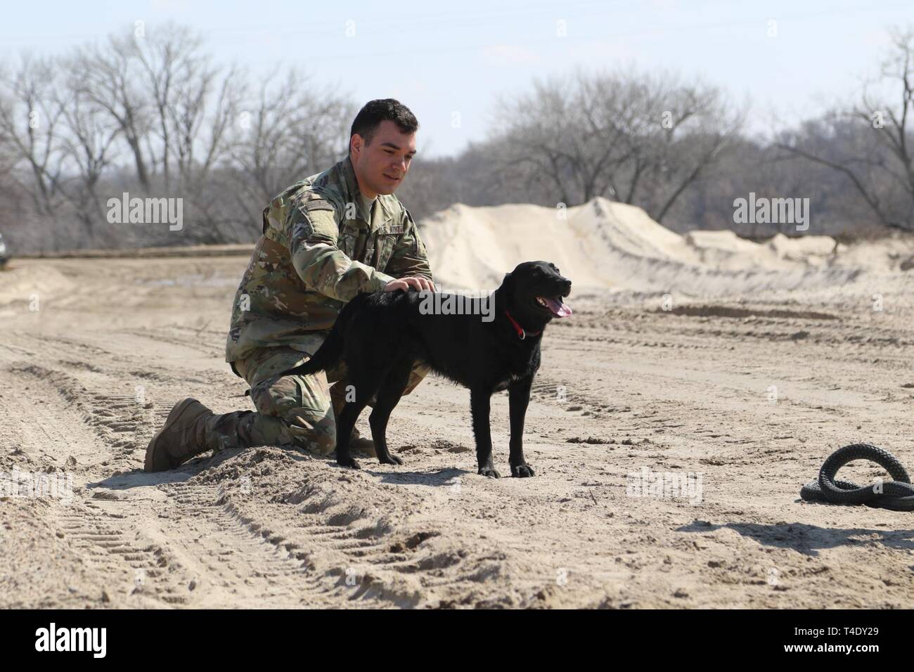 Il Nebraska Esercito Nazionale soldato di guardia, Sgt. Luis Rocha, 195th, Intendente di distacco, Rigger Team di supporto (RST), prende un momento al PET un cane prima di imbracatura operazioni di carico vicino a Genova, Nebraska, Marzo 26. Rocha e altri riggers erano parte di un team che ha preparato un Bobcat caricatore per il trasporto di aria durante il diluvio gli sforzi di recupero al fiume Loup diga di diversione. (Nebraska Guardia Nazionale Foto Stock