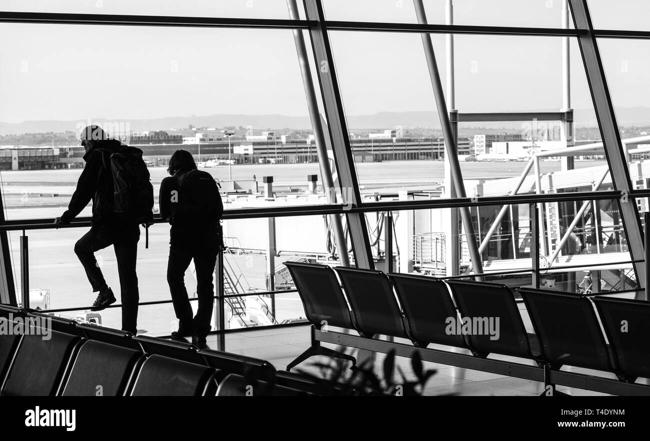 Stoccarda, Germania - Mar 26, 2016: Adulto Giovane Aeroporto ammirando il paesaggio con edifici e piani dal sightseeing ampia finestra di visualizzazione - bianco e nero Foto Stock