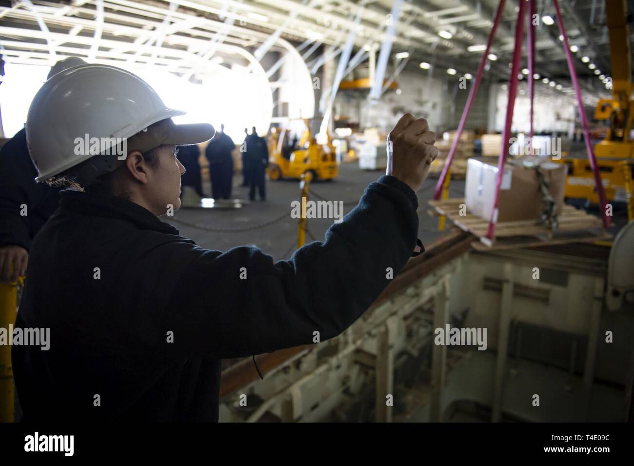 Va. (27 marzo 2019) Capo Logistica Specialista Vicki pagine, da Yabucoa, Puerto Rico, i segnali al gruista nell'hangar bay della portaerei USS Dwight D. Eisenhower CVN (69). Ike è sottoposto a una prevista disponibilità incrementale (PIA) durante la fase di manutenzione della flotta ottimizzato il piano di risposta (OFRP). Foto Stock
