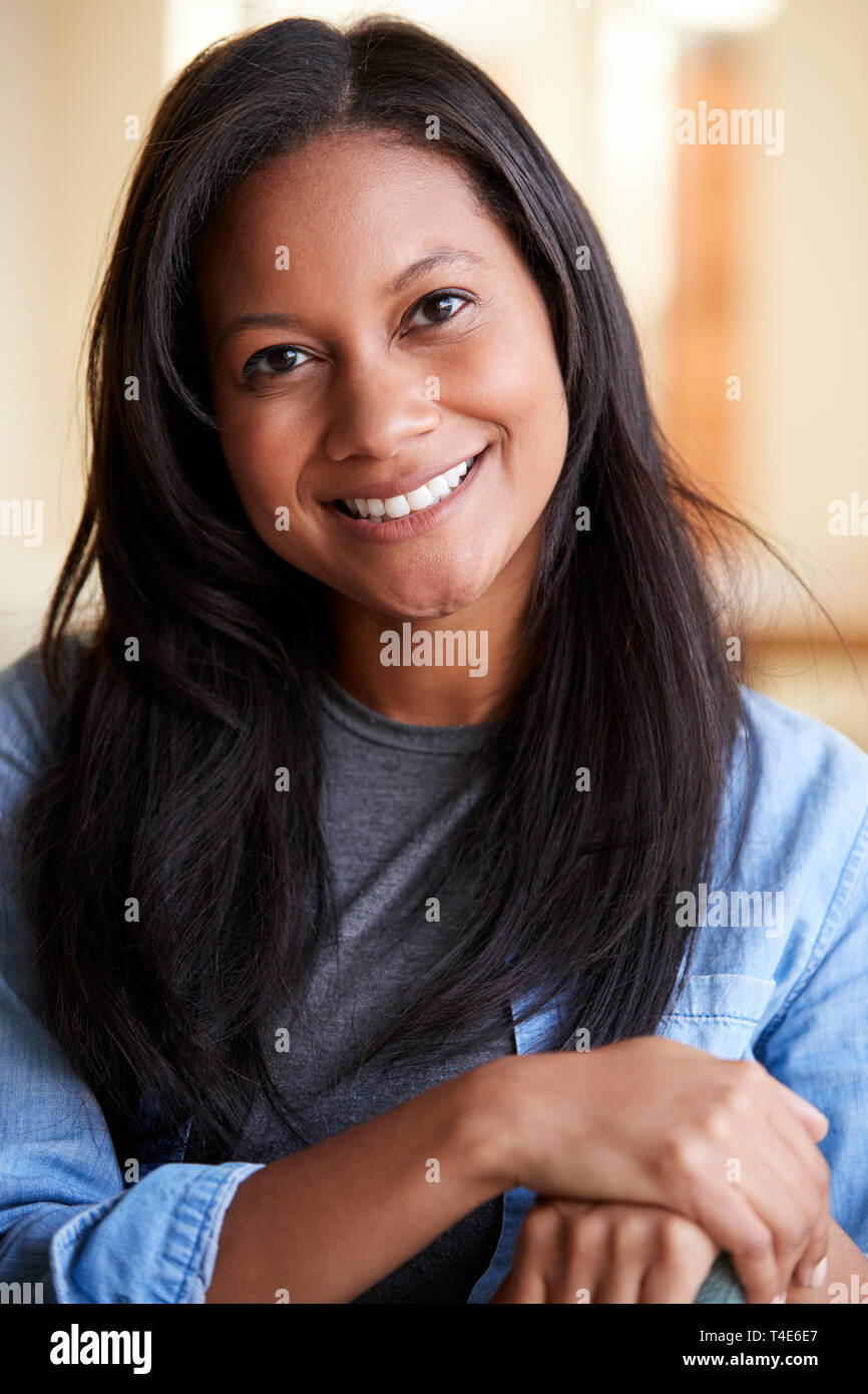 Ritratto Di Donna sorridente rilassante sul divano di casa Foto Stock