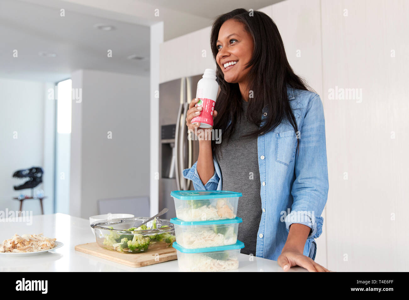 La donna in cucina la preparazione di pasto sano bere Protein Shake da bottiglia Foto Stock