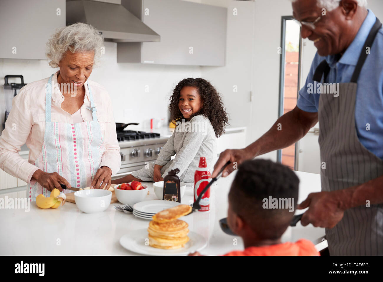 Nonni In cucina con i nipoti fare frittelle insieme Foto Stock