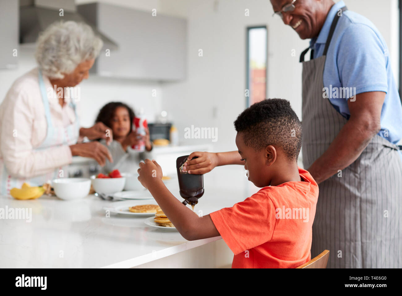 Nonni In cucina con i nipoti fare frittelle insieme Foto Stock