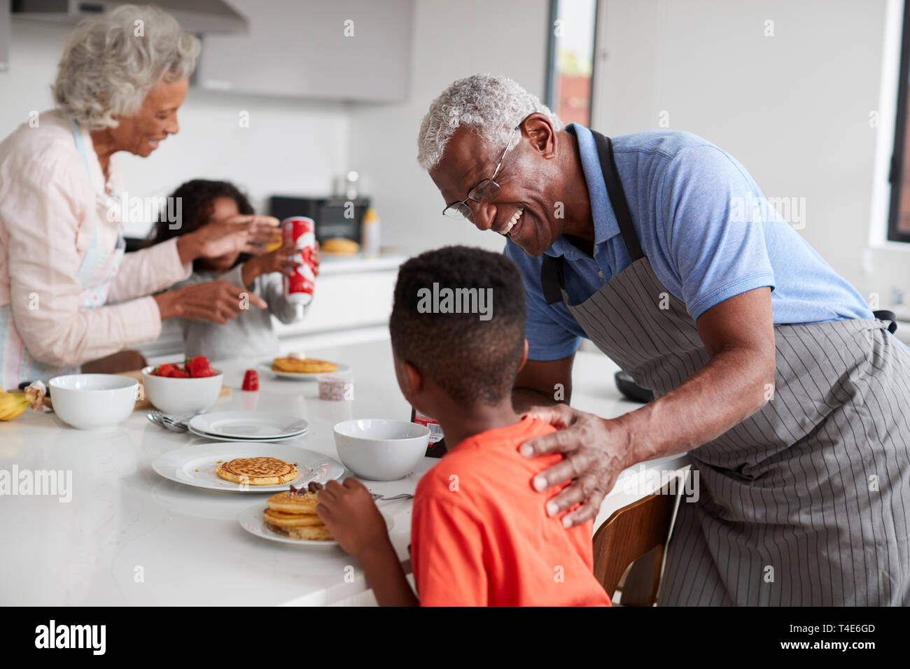 Nonni In cucina con i nipoti fare frittelle insieme Foto Stock