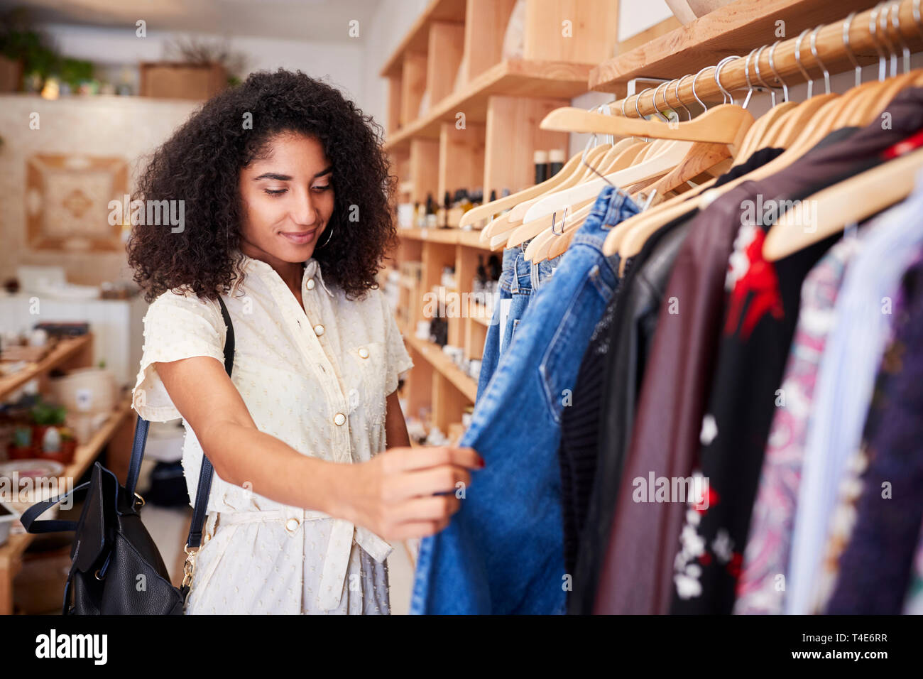 Femmina Shopping cliente indipendente in un negozio di abbigliamento guardando i rack Foto Stock