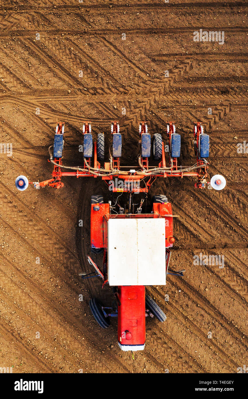Vista superiore del trattore con una seminatrice da fuco pov, astratto minimo composizione in miniatura di macchine agricole in campo arato per impiantare coltivazioni Foto Stock