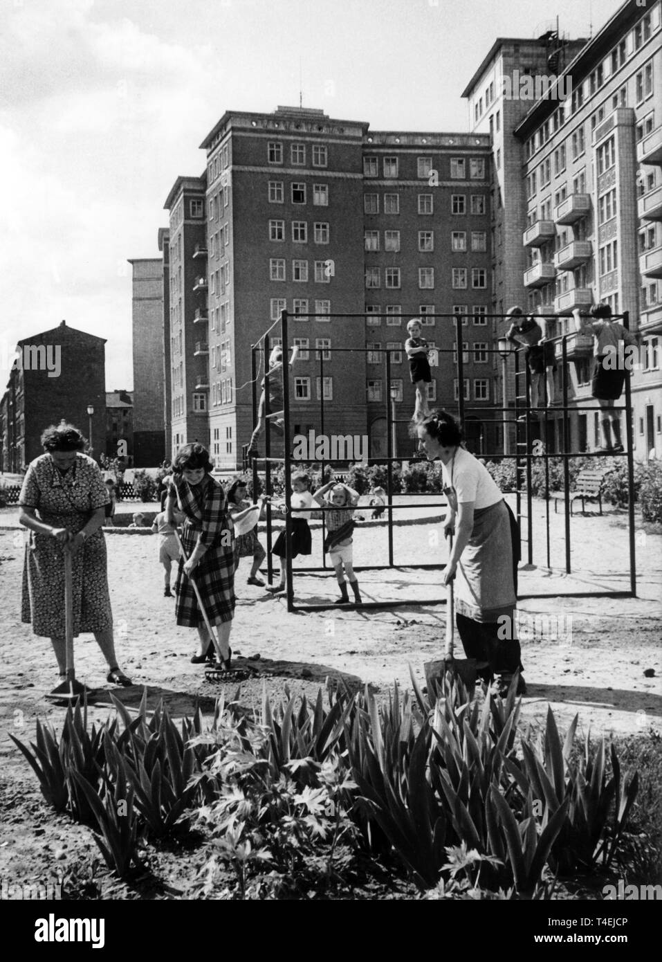 Die freiwilligen Helferinnen (l-r) Erna Wuttke, Ilse Rotkirch und Dorothea Meister bei der Arbeit am 14.05.1957. Im Hintergrund Kinder auf dem Klettergerüst. Hinter dem blocco B Süd in der Stalinallee in Ostberlin haben die Einwohner blocchi des in freiwilligen Arbeitseinsätzen eine Grünanlage mit Kinderspielplatz geschaffen. Es wurden seit 1955 1806 Arbeitsstunden geleistet. | Utilizzo di tutto il mondo Foto Stock