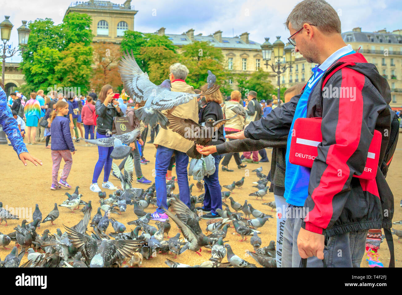 Parigi, Francia - luglio 1, 2017: i piccioni alimentazione di Notre Dame piazza piena di gente. Giovane turista gode di Parigi. Una popolare destinazione turistica in francese Foto Stock