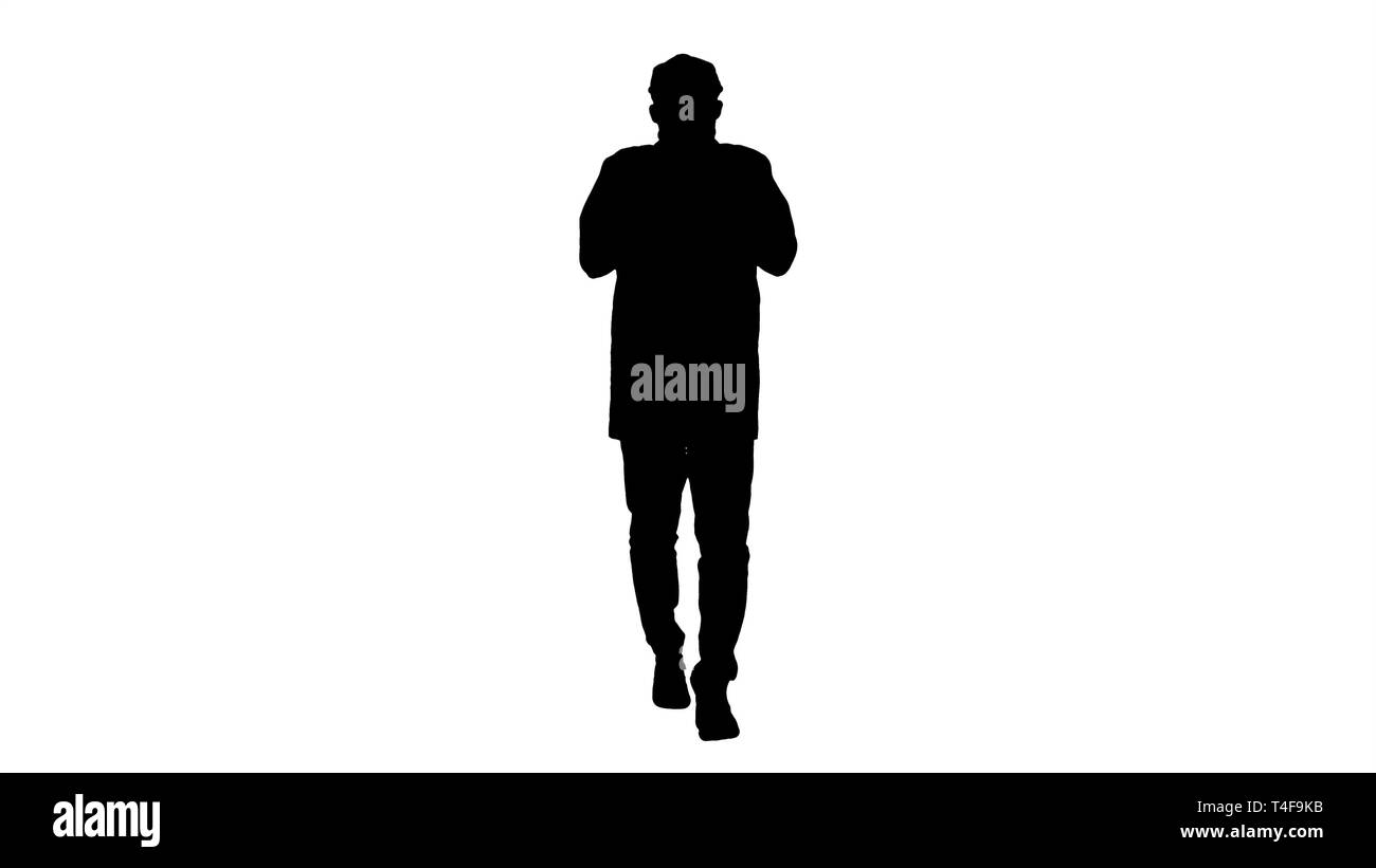 Silhouette giovane uomo bello passeggiate e i pulsanti up mantello. Foto Stock