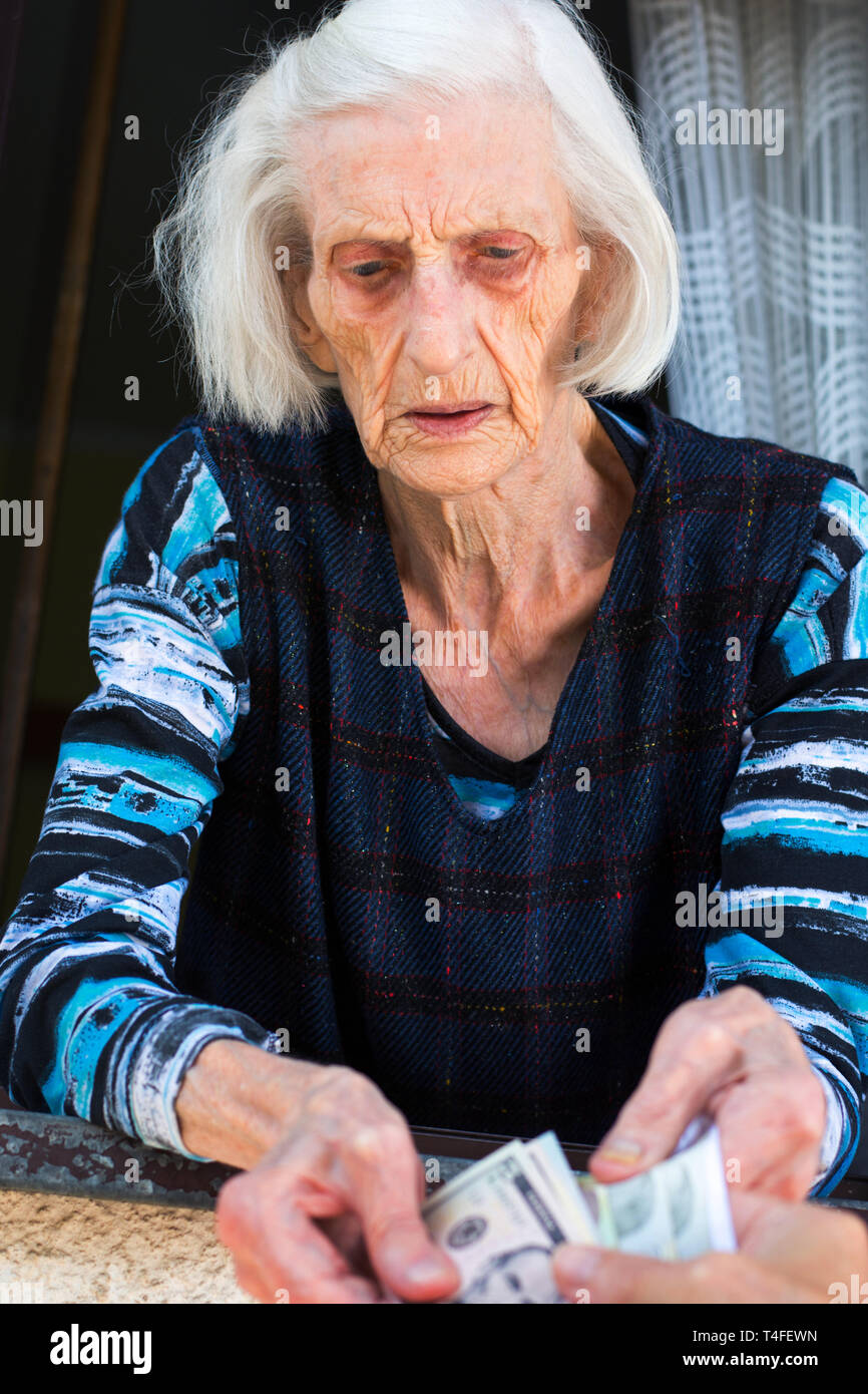 Nonna contando il pensionamento denaro a casa sulla finestra a casa Foto Stock