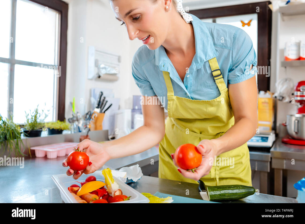 Donna sorridente in cucina tenendo i pomodori Foto Stock