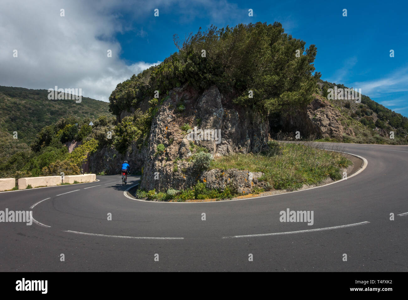 Drammatica vista di un ciclista su strada in bicicletta pedalando un tornante nel Parque Rural de Anaga park, TF-12 Tenerife, Spagna Foto Stock