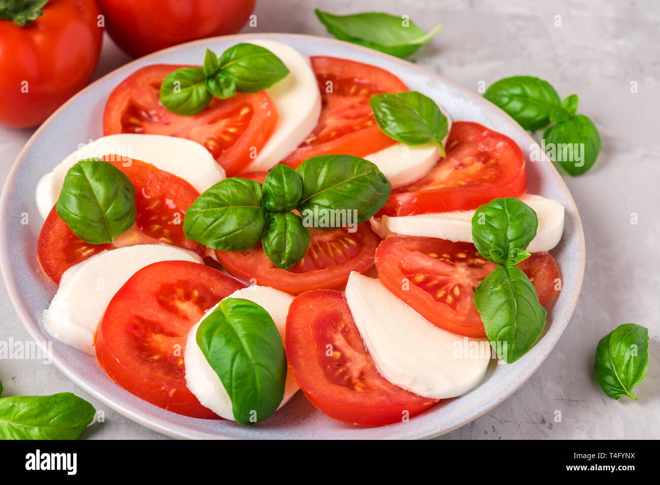 Insalata caprese con pomodori maturi e mozzarella, di foglie di basilico fresco su calcestruzzo sfondo. Il cibo italiano. close up Foto Stock