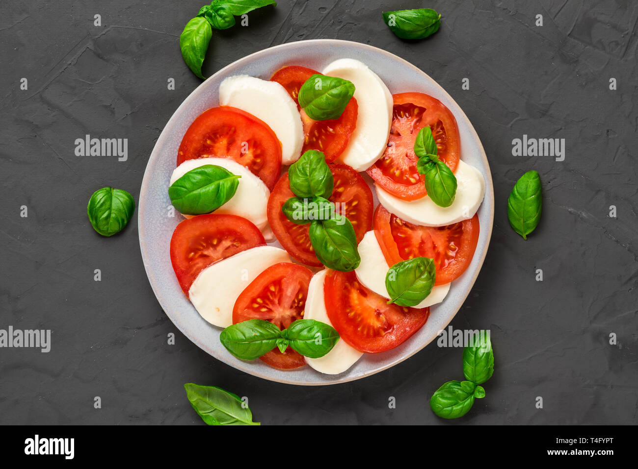 Piastra di italiano insalata caprese in una piastra più scuro dello sfondo concreto. cibo sano. vista superiore. laici piatta Foto Stock