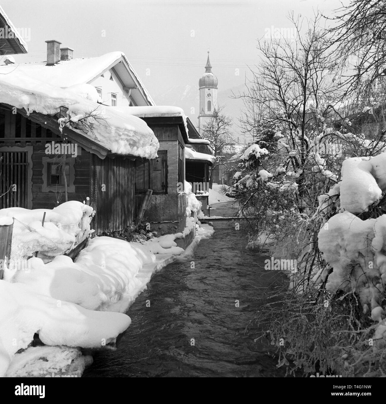 Vista di un flusso accanto al coperto di neve e le case e il campanile di una chiesa in presenza di neve Garmisch-Partenkirchen (non datato foto di archivio da gennaio 1963). | Utilizzo di tutto il mondo Foto Stock