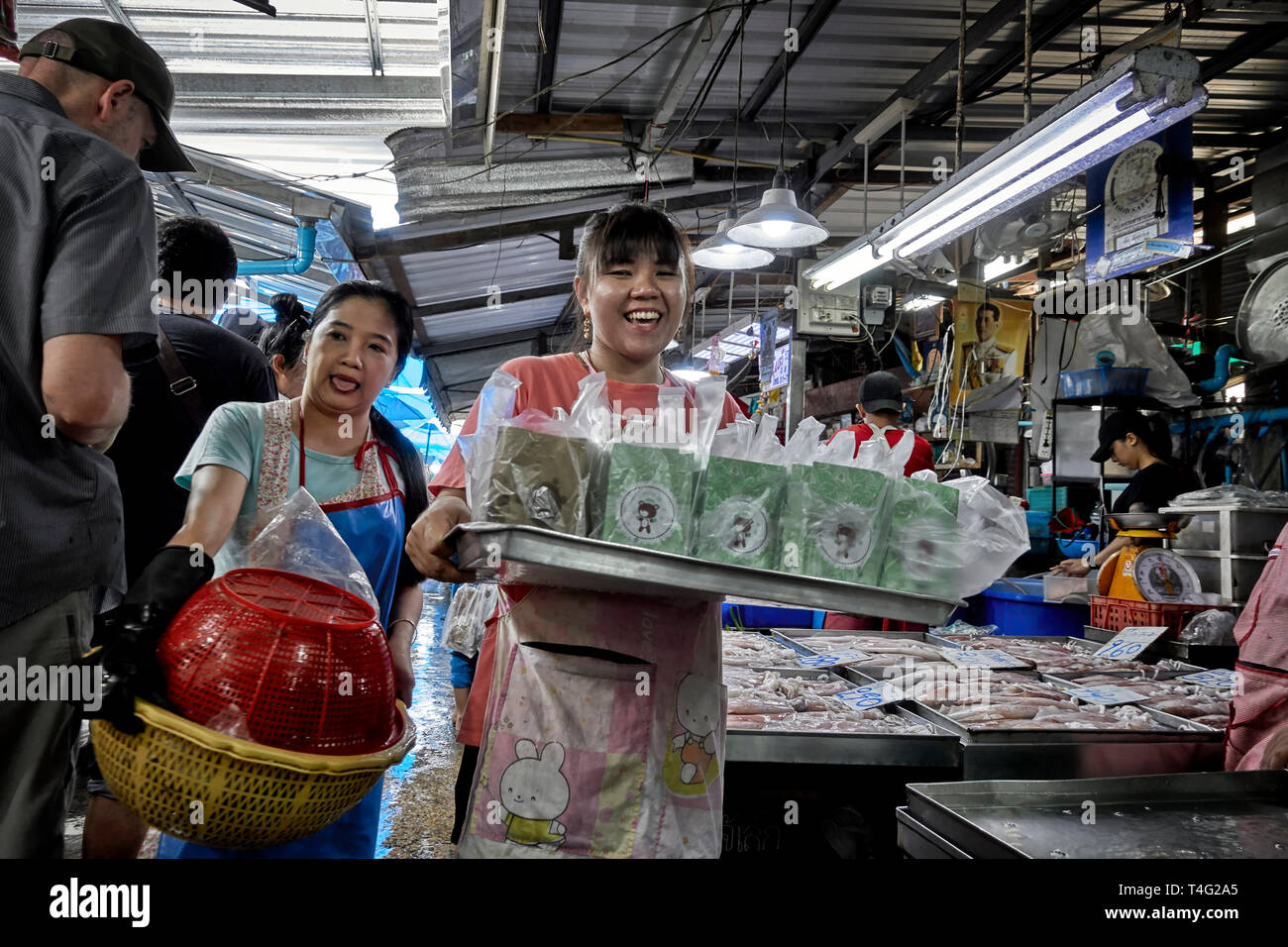 Felice e sorridente donna Thai portando un vassoio di contenitori per alimenti in un mercato della Thailandia, Sud-est asiatico Foto Stock