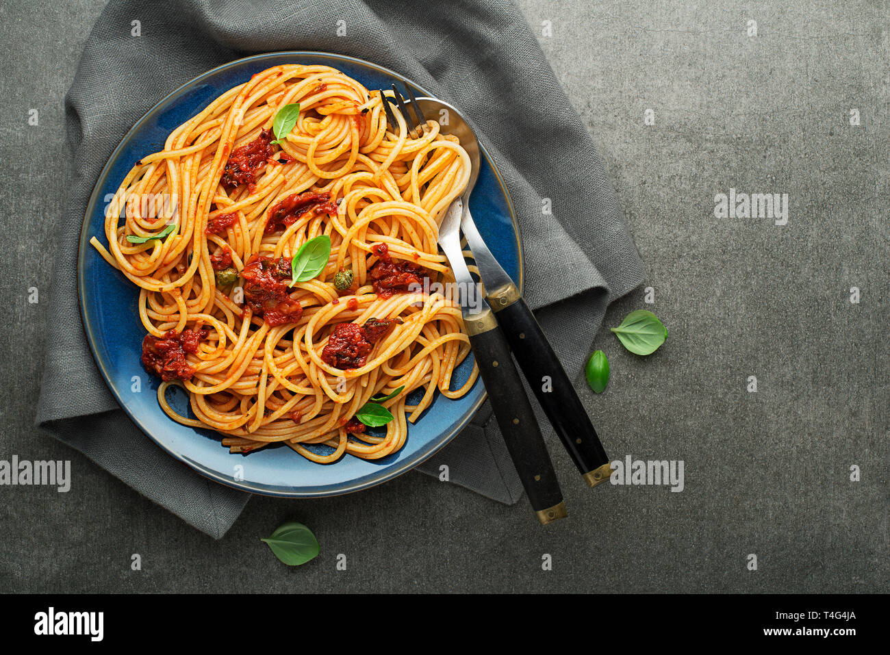 Pasto delizioso con gli spaghetti e salsa di pomodoro con basilico servito su sfondo grigio Foto Stock