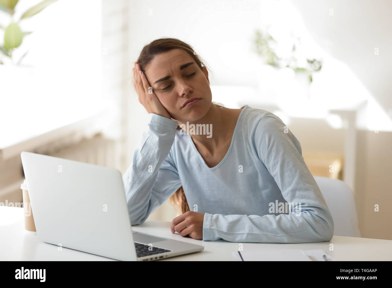 Stanco donna che dorme sul desktop nella parte anteriore del computer Foto Stock