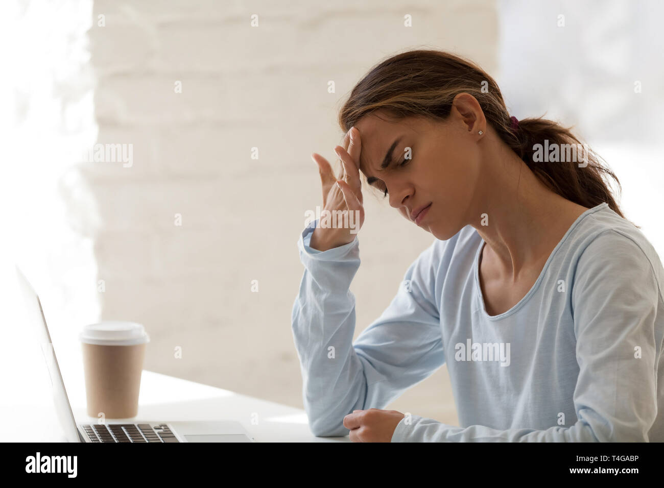Donna con mal di testa emicrania al desktop in ufficio Foto Stock