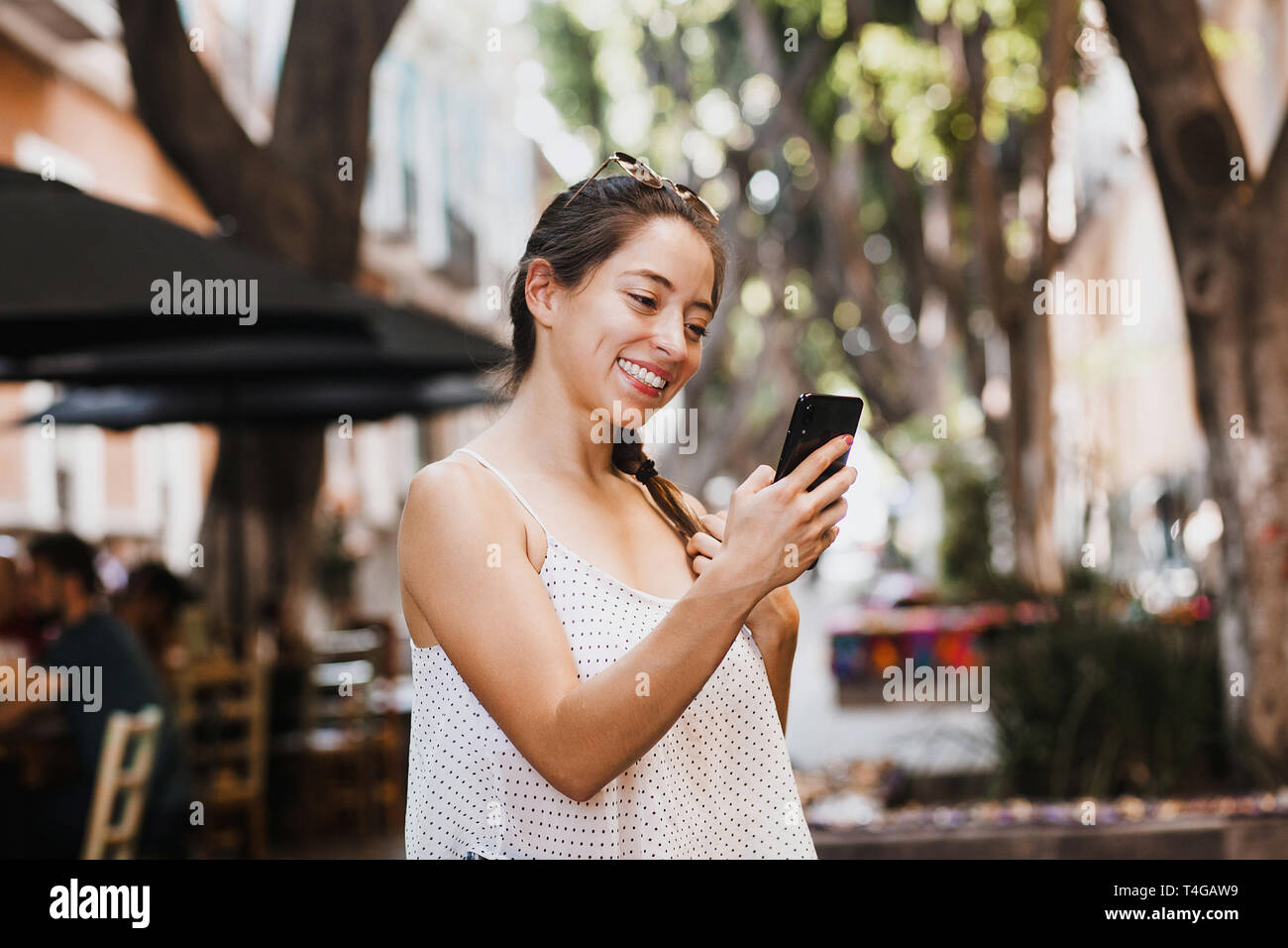 Giovane donna latina messaging tramite telefono indossando abiti casual in Messico Foto Stock