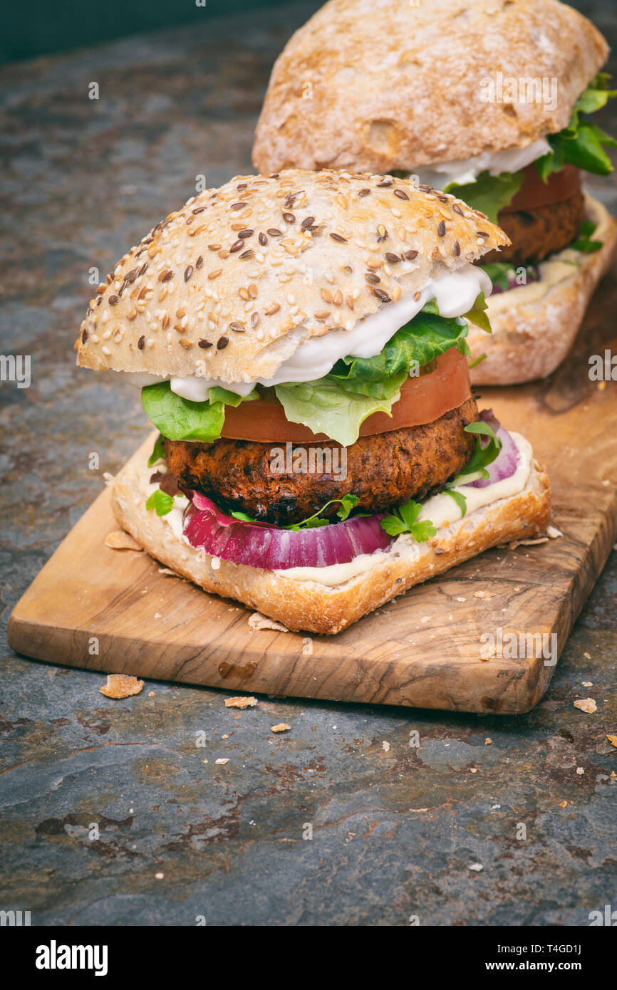 Hamburger vegano su di un legno d'ulivo scheda su ardesia Foto Stock