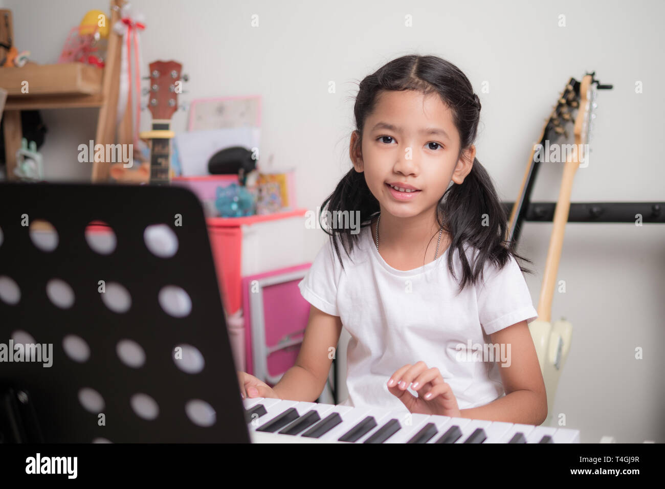 Asian bambina di imparare a suonare il pianoforte tastiera sintetizzatore e  sorridi con la felicità, ragazza tailandese studiare la musica a casa Foto  stock - Alamy