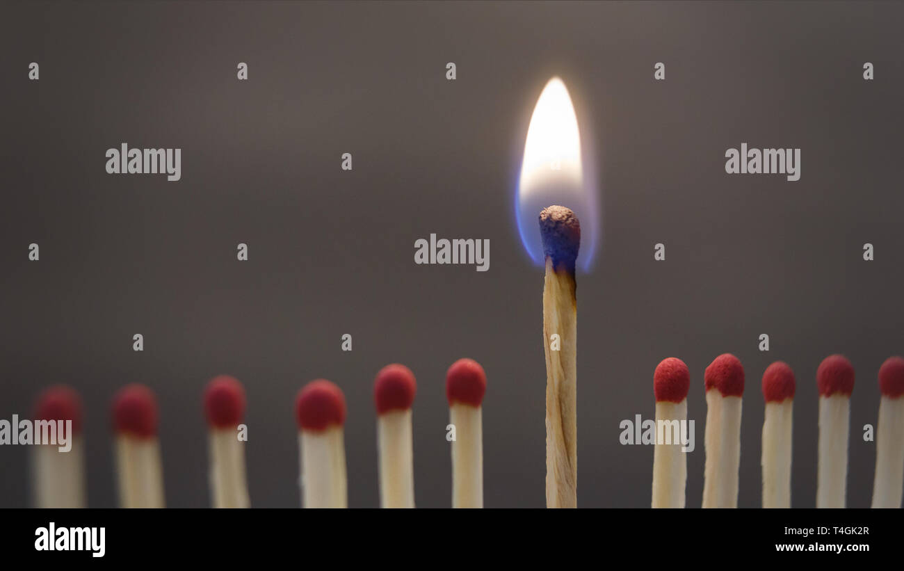 Un fiammifero che brucia tra quelle rovinate su nero Foto Stock