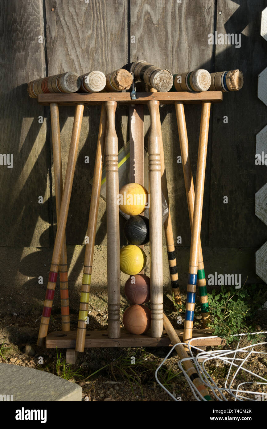 Il vecchio ben utilizzato Croquet Mallets in un rack, appoggiata contro una parete in legno Foto Stock