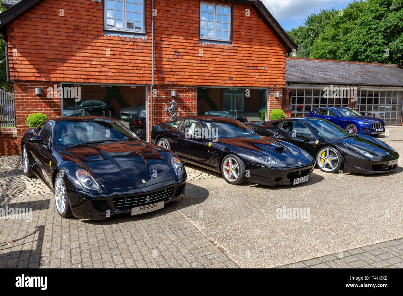 Diversi di colore scuro Ferrari auto sportive tra cui una Ferrari 599 GTB parcheggiata fuori Meridien Modena, Lyndhurst, Hampshire, Regno Unito. Foto Stock