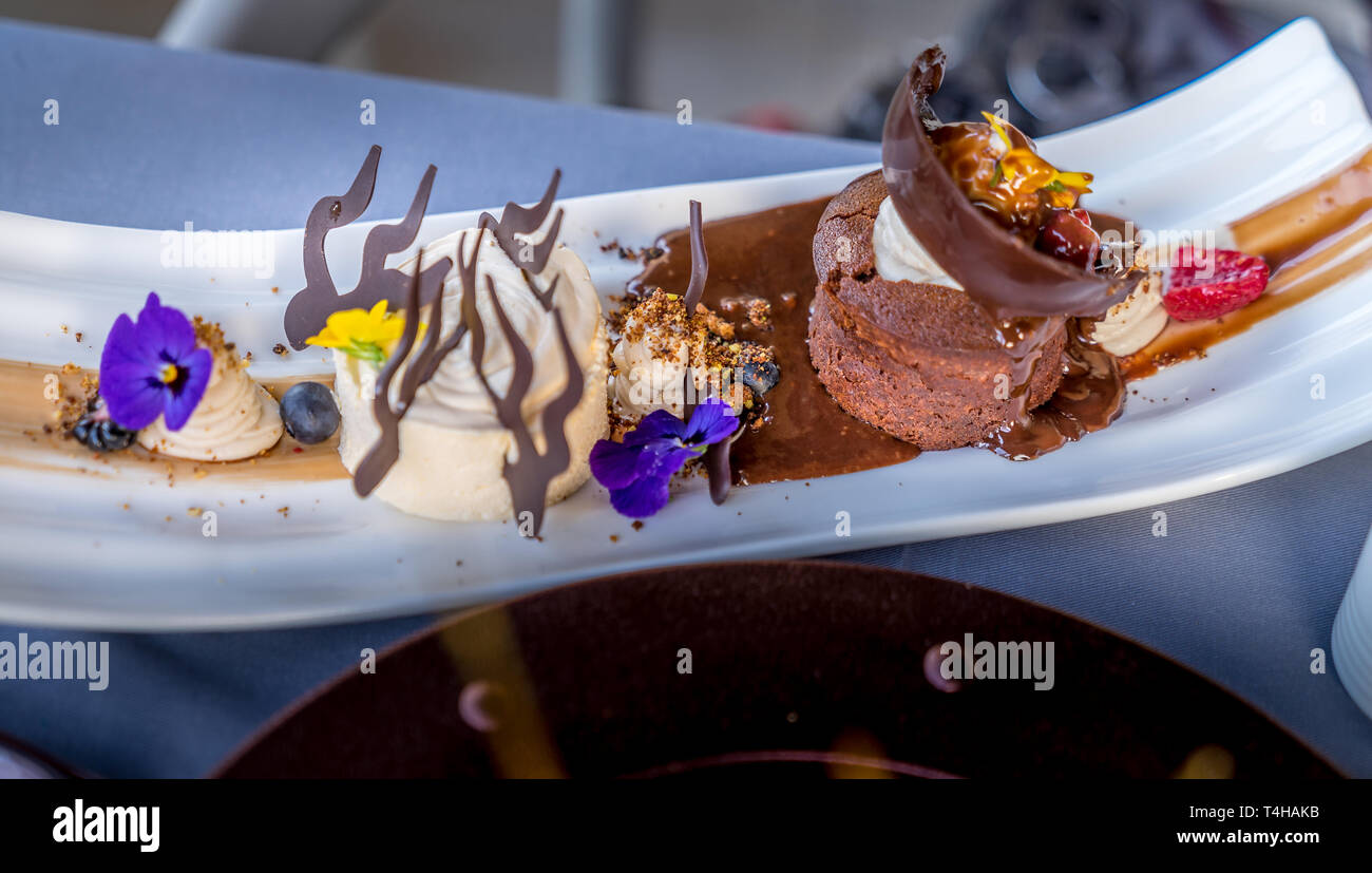 Caldo Torta al cioccolato con baccelli di vaniglia Gelato al cioccolato, frollini. decorate con violette fresche e pansies giallo. Foto Stock