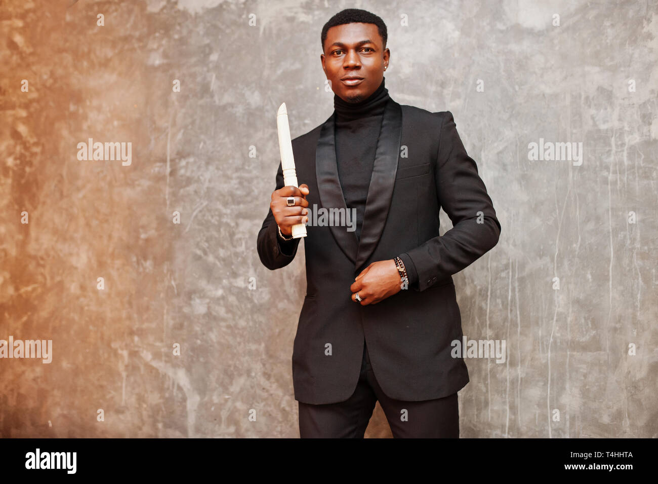 Forte potente african american man in black suit e turtleneck con elephant brosmio. Foto Stock