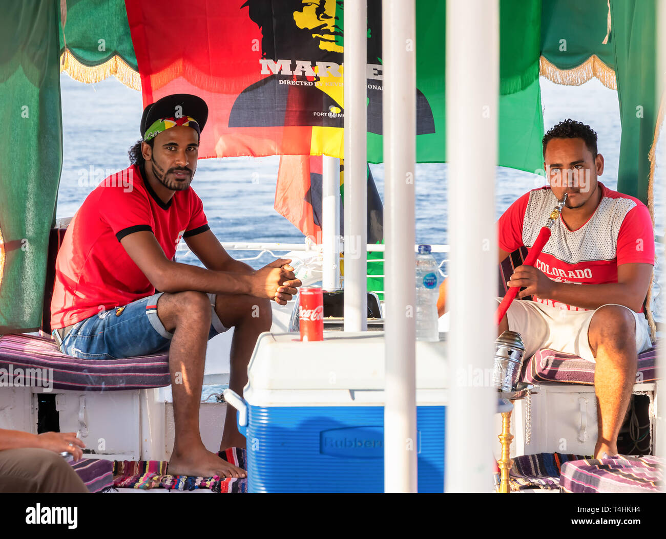 Aswan, Egitto - 13 Settembre 2018: egiziana uomini fumatori shisha tubo mentre la vela in un motoscafo turistica nel fiume Nilo Foto Stock