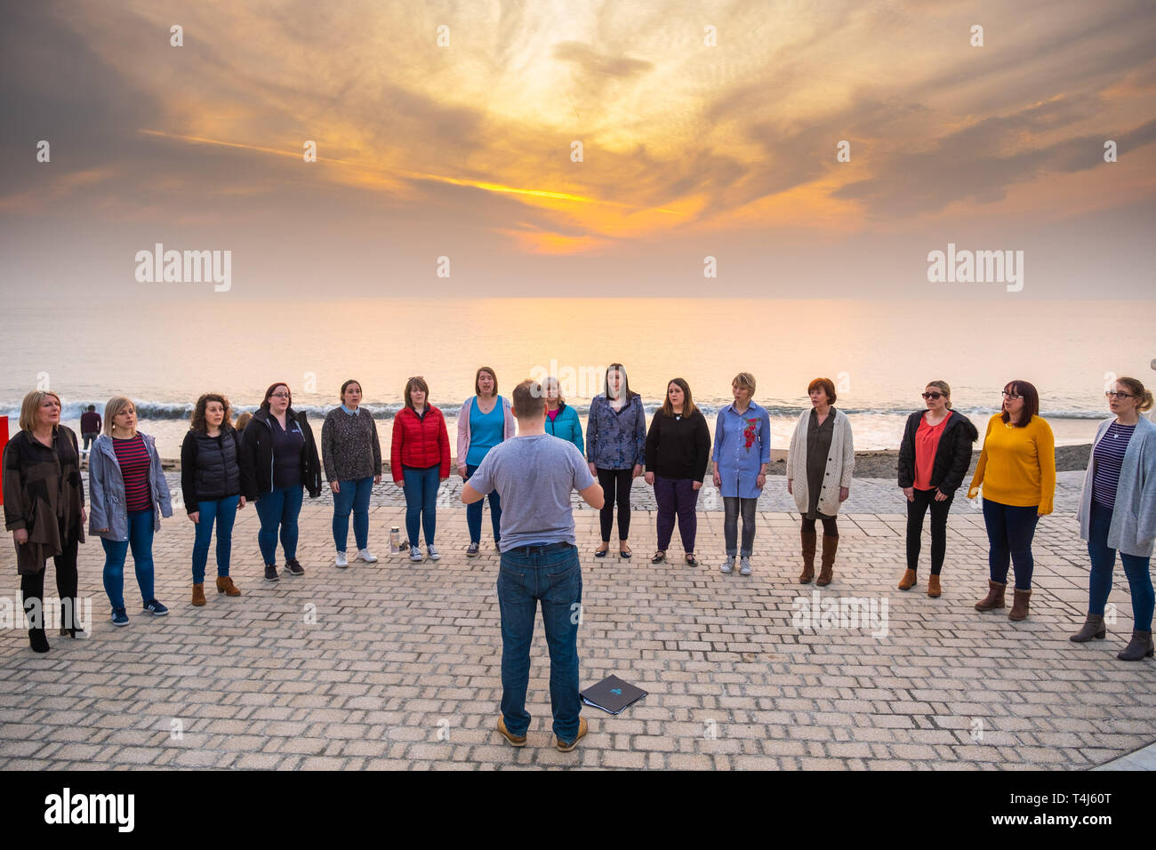 Aberystwyth Wales UK, mercoledì 17 aprile 2019 UK Meteo: un gruppo di donne , i membri del 'Merched ger y Lli' [ il Welsh per 'Ragazze dal mare'] coro hanno una improvvisata di prove e prestazioni sul lungomare al tramonto del sole alla fine di una calda e soleggiata giornata di primavera in Aberystwyth Wales. Il clima è guidato su un miglioramento della via , con molto caldo nei prossimi giorni come il paese attende le vacanze di Pasqua. Credito foto Keith Morris / Alamy Live News Foto Stock